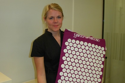 Jessica Lindblom håller upp en lila spikmatta med vita spikar.