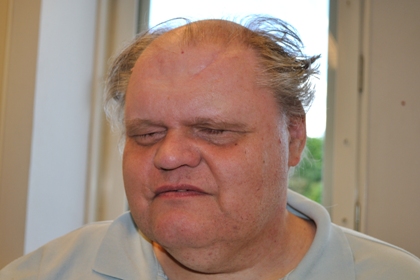 Leif Jeppsson har lite hår högst upp på huvudet, håret på sidorna har gråvita stänk. Han har slutna ögon, en gråvit pikétröja och ett brett ansikte.