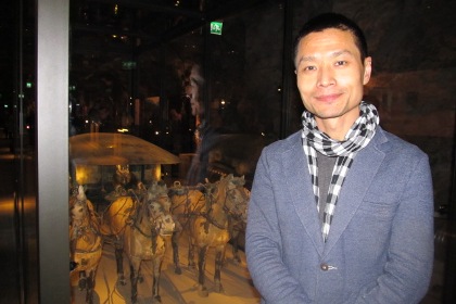 Si Han intendent på Östasiatiska museet står framför en av utställningsmontrarna.