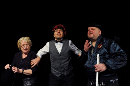Fotograf: Mansour Hosseini. En scen ur ”Ett skakigt äventyr”. Från vänster Gurli Wåglund i lila glitterklänning. Carlos Müller Villanueva med huvudbonad och Rolf Eriksson med vit käpp klädd som Elvis