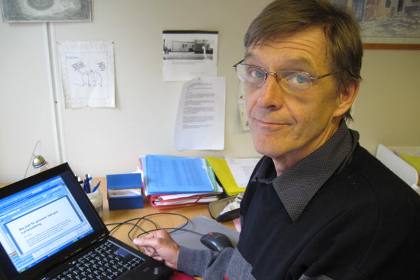 Bertil Sköld har kort brunt hår och glasögon. Han sitter framför sin dator.
