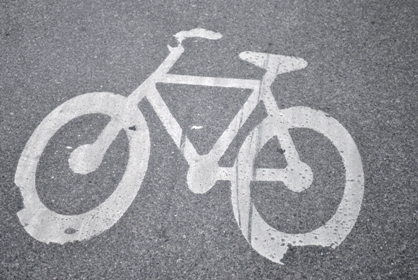 Bild av markering på cykelbana; en vit cykelsiluett målad på grå asfalt.