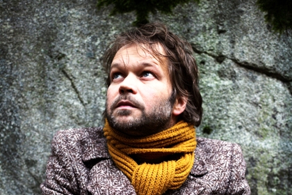 Tomas Bannerhed har mörkt skägg och hår och en stor gul halsduk om halsen.