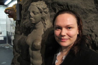 Jenny Stenbeck har hög panna och svart bakåtkammat halvlångt hår. Hon bär en svart tröja med öppen hals.