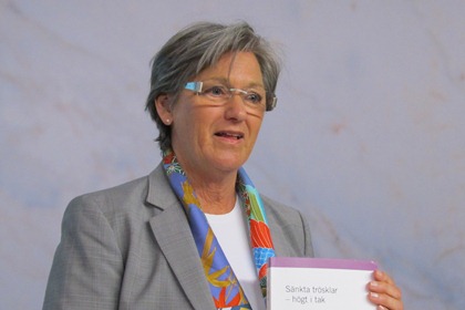 Christina Husmark Persson har grått kortklippt hår, båglösa glasögon, grå kavaj och en färgglad scarf.