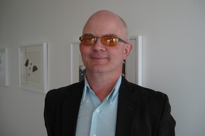 Arvid Lindén är iklädd kavaj, orange glasögon och mycket kort hår