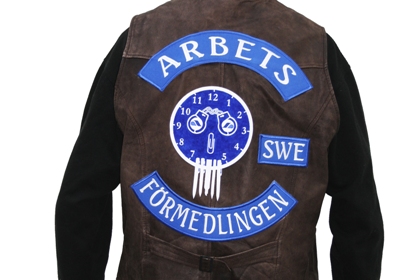Skinnväst med texten Arbetsförmedlingen och ett emblem med pennor som liknar tänder och handklovar som liknar ögon.