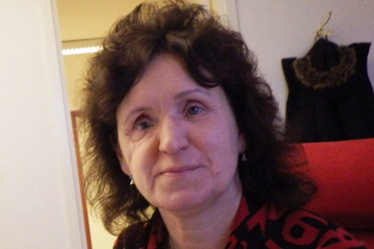 Lena Höjdevall har mörkt, lockigt axellångt hår och svart tröja med rött mönster.