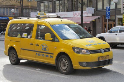 En gul taxibil från Taxi 020 kör förbi på Götgatan